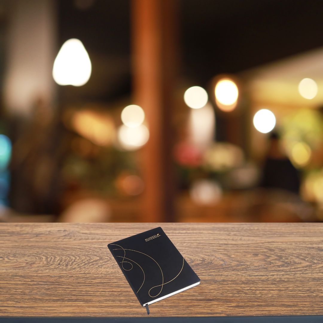 Premium A5 business notebook with golden cursive design on a wooden desk