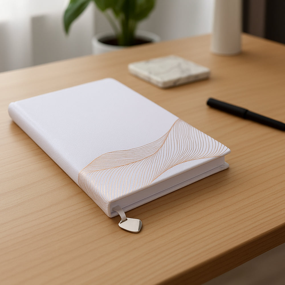 Wave White A5 hardbound notebook with rose gold leafing and metal bookmark ribbon on desk